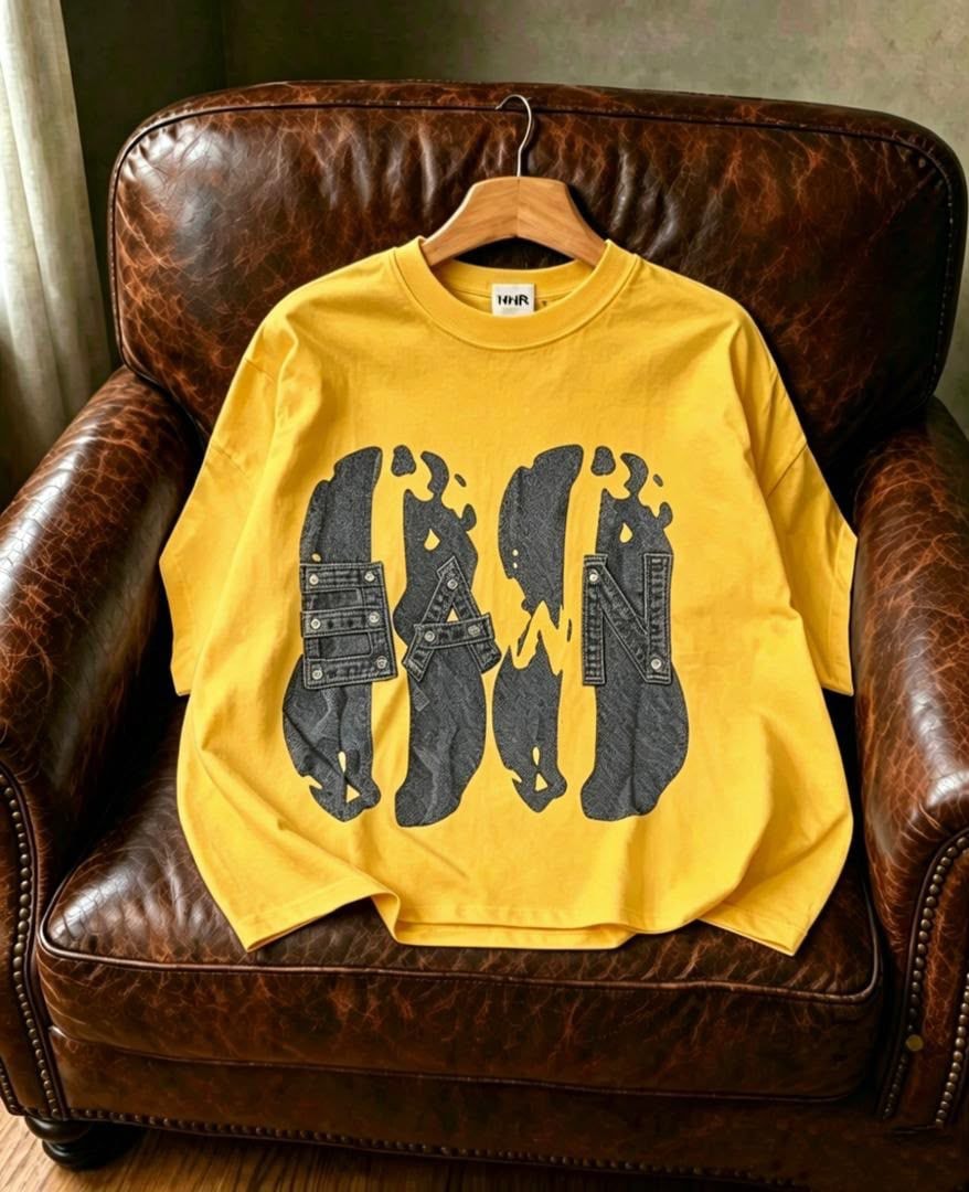 Yellow Dawn graphic t-shirt with stylized lettering, displayed on chair.