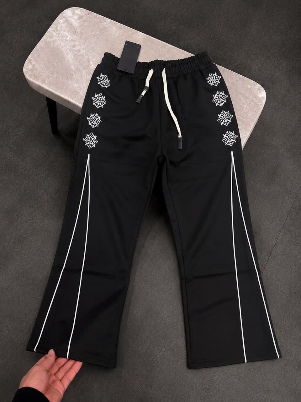 Black joggers with white embroidery and side stripes laid flat.