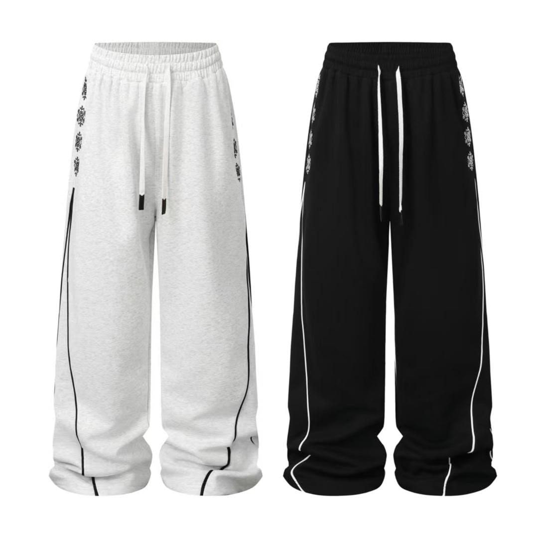 Black and gray joggers with side embroidery and stripes displayed side by side.