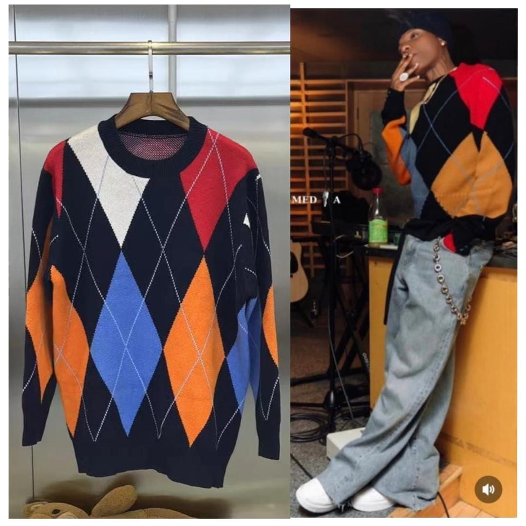 Unisex argyle knit sweatshirt shown hanging on a wooden hanger and worn by a model in studio setting.