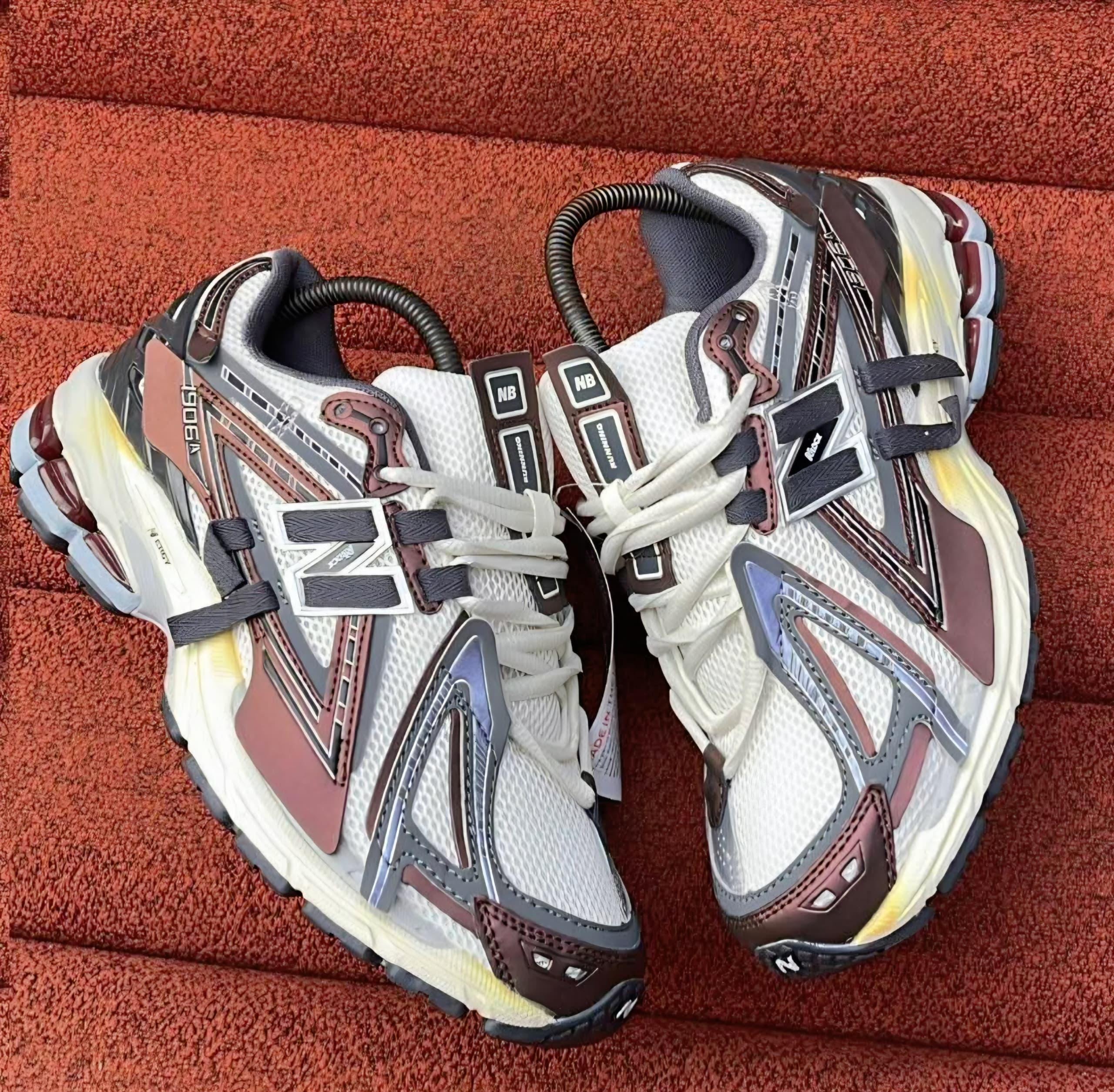 White brown and gray New Balance 9060 chunky sneakers on red textured surface.