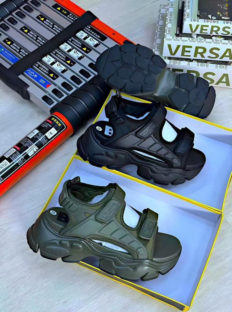 Black and olive green Buffalo chunky sandals displayed in yellow boxes with one showing the rugged sole.