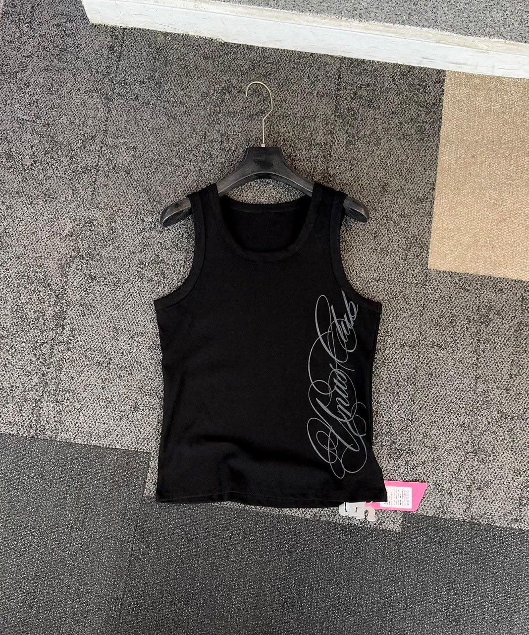 Black armless tank top with silver cursive script print on the side, hanging on a black hanger.