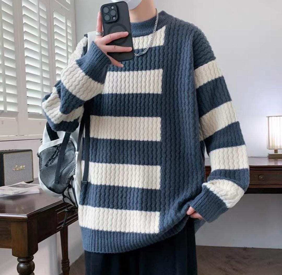Model wearing blue and white striped chunky knit sweatshirt holding phone.