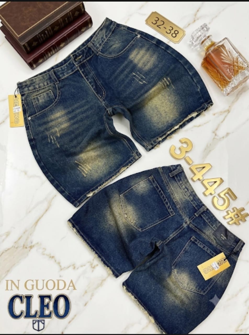 Front and back views of faded blue denim shorts with rips on marble surface with books and decanter.