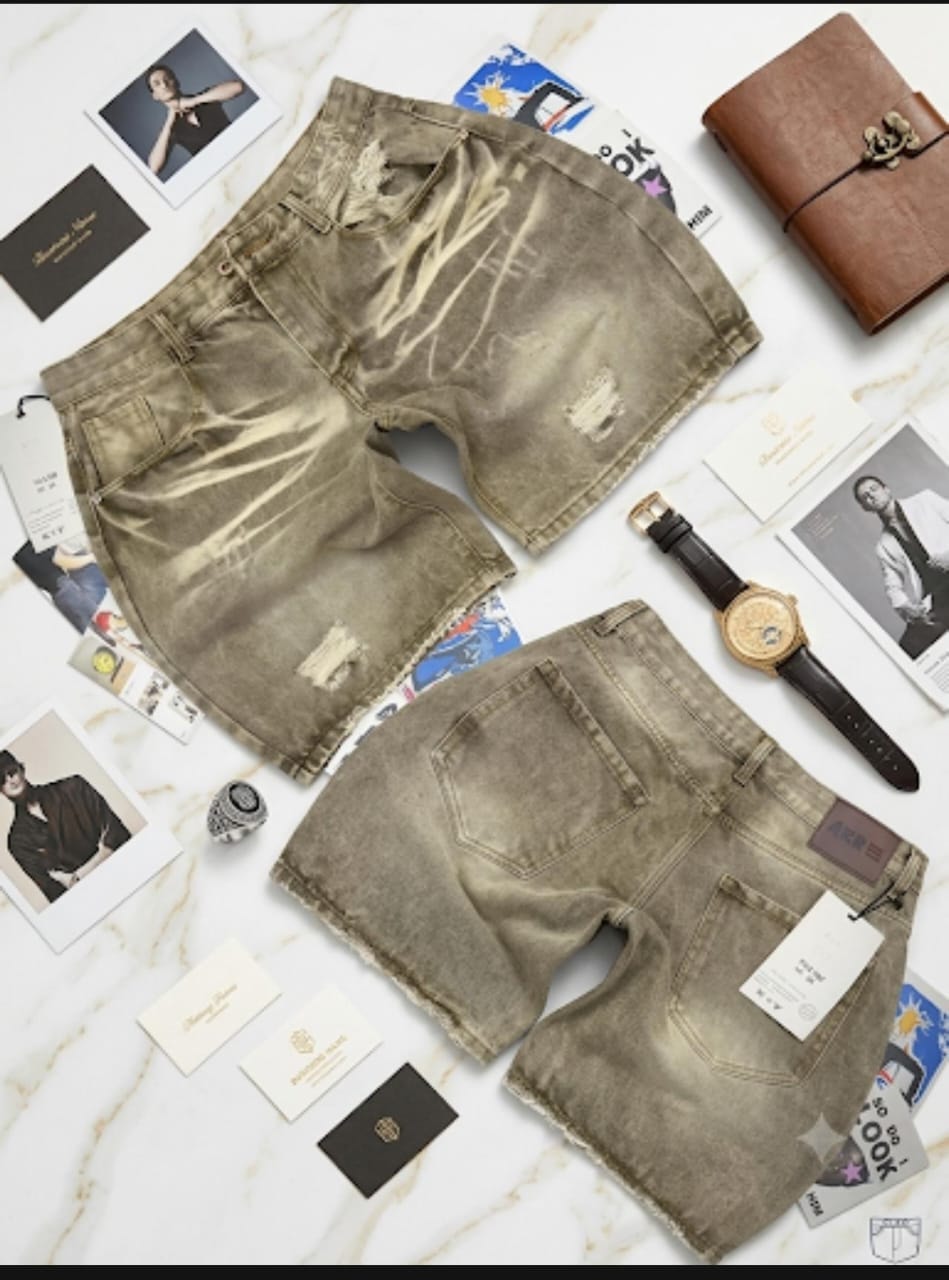 Front and back views of beige distressed denim shorts surrounded by fashion props and business cards.
