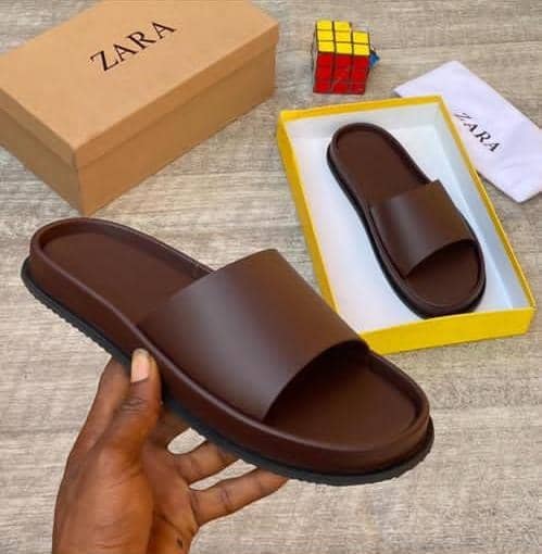Brown Zara slide held in hand with box and packaging in background.