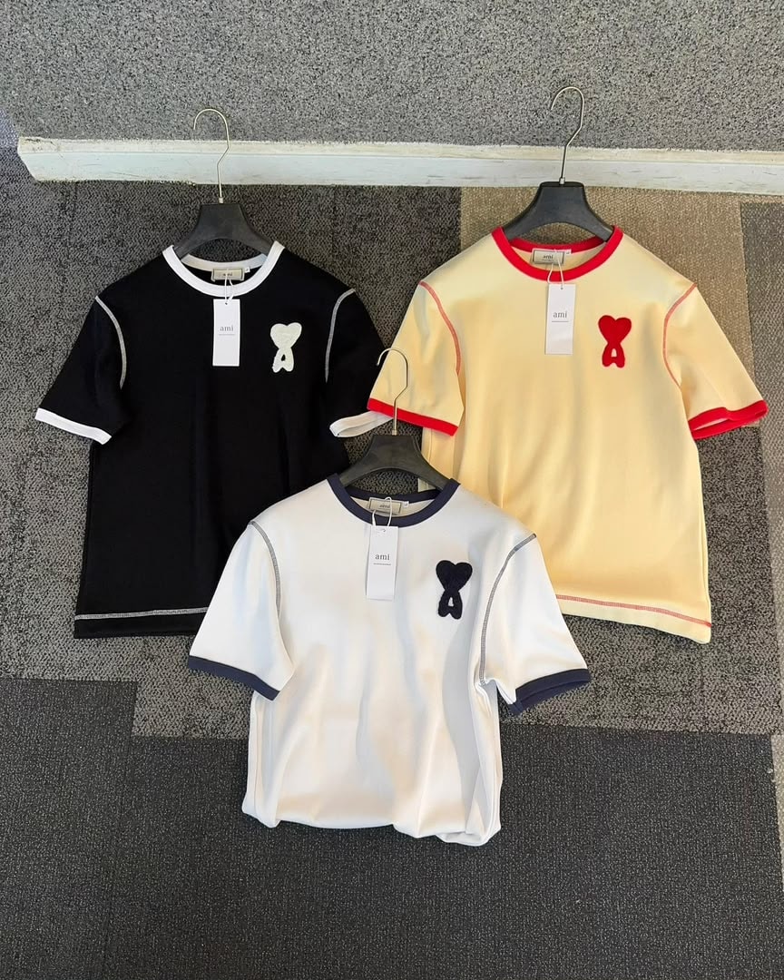 Three AMI polo shirts in black, white and cream colorways displayed together.