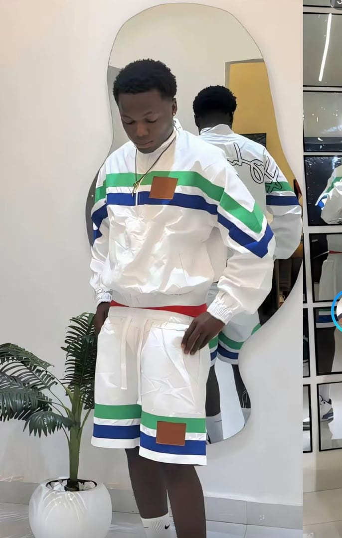 Model wearing white striped windbreaker jacket and shorts with green blue stripes and brown patches.