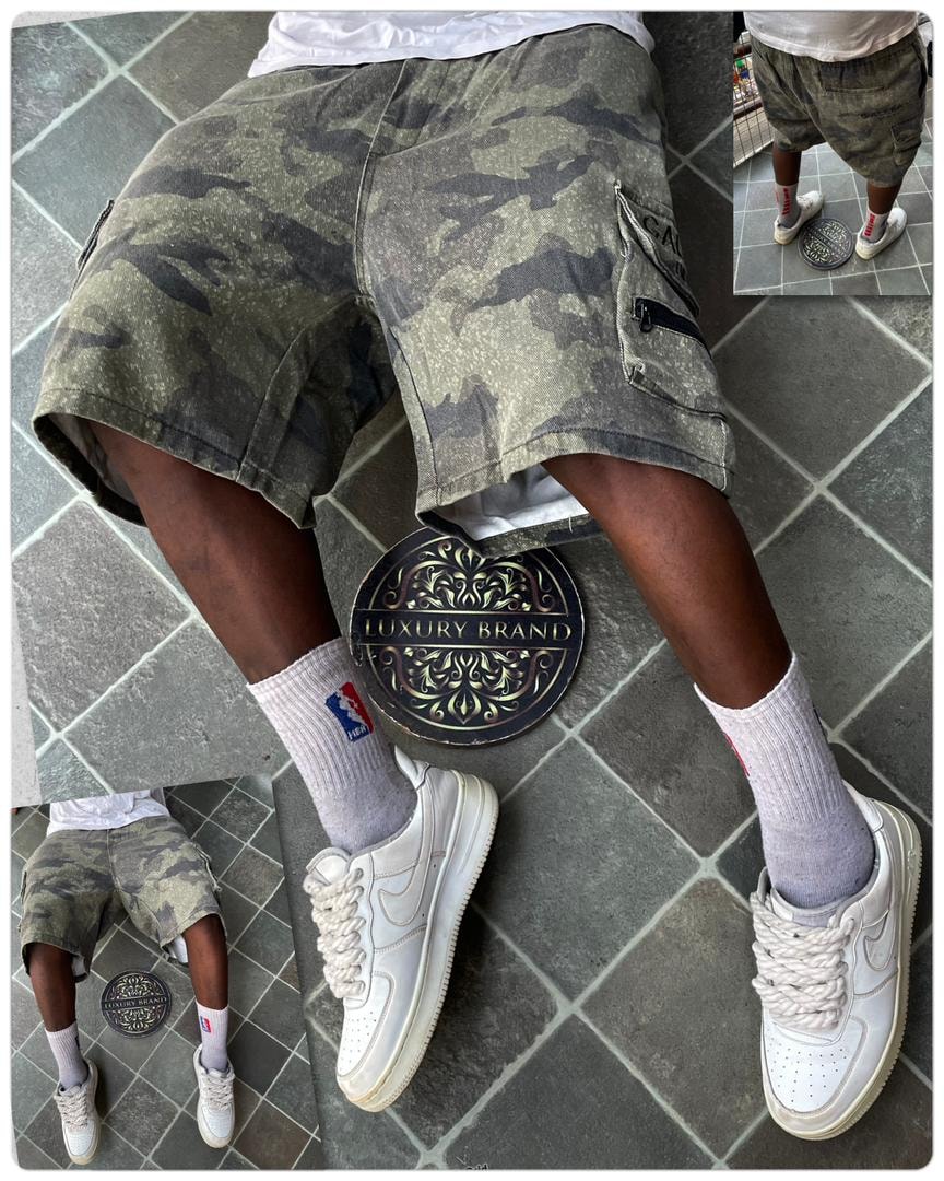 Model in green camo cargo shorts with luxury brand mat and white sneakers.