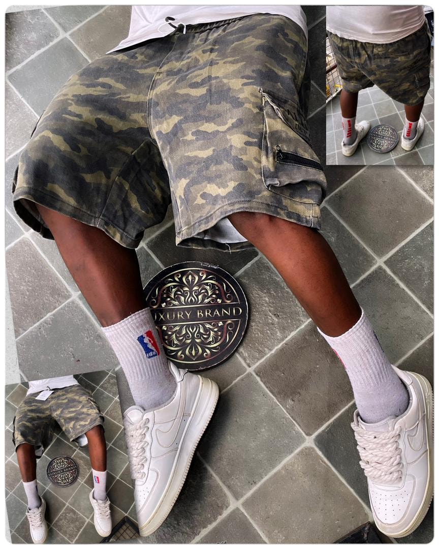 Model wearing green military camo cargo shorts with white top, NBA socks and white sneakers.