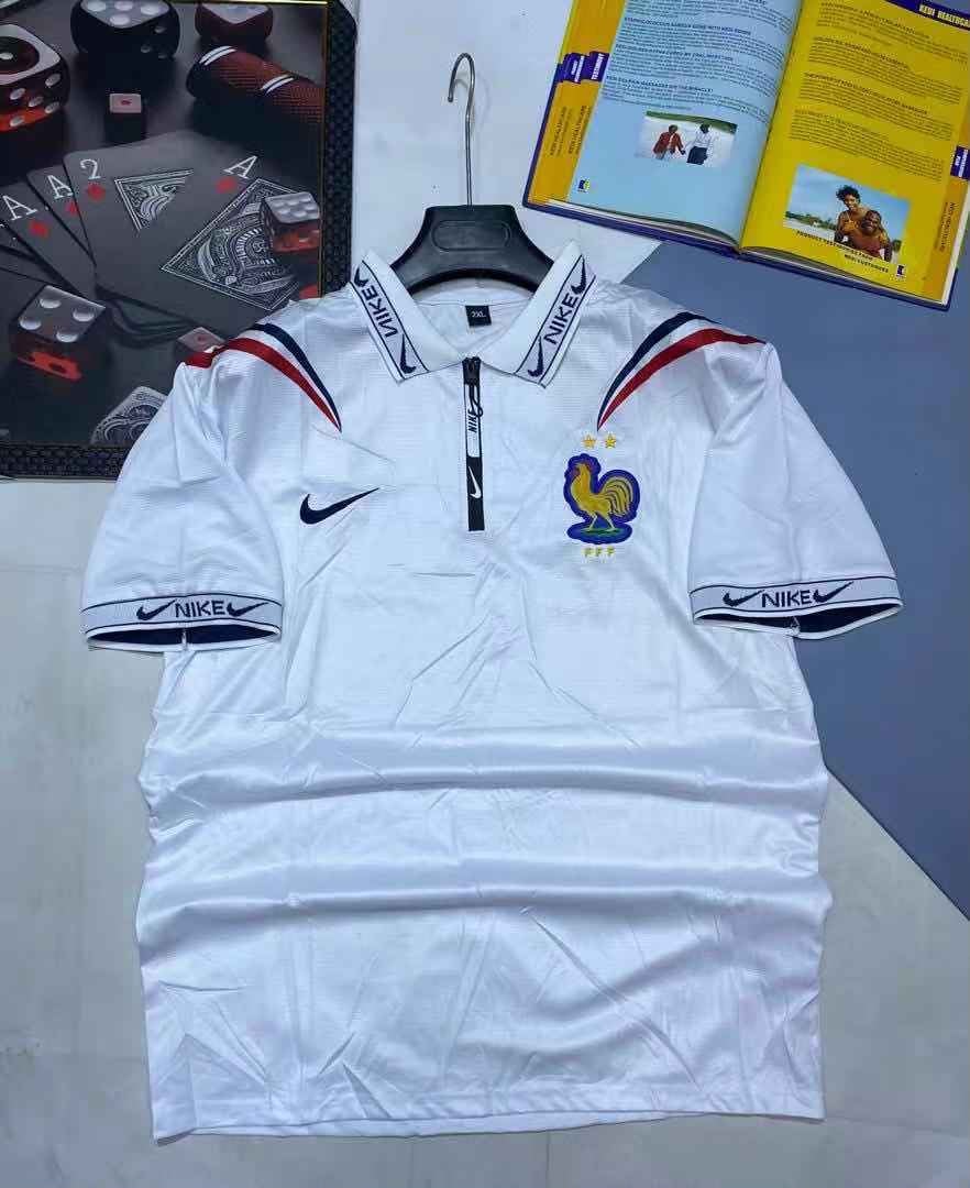 White Nike France football jersey with rooster crest, zip collar and shoulder accents hanging on rack.