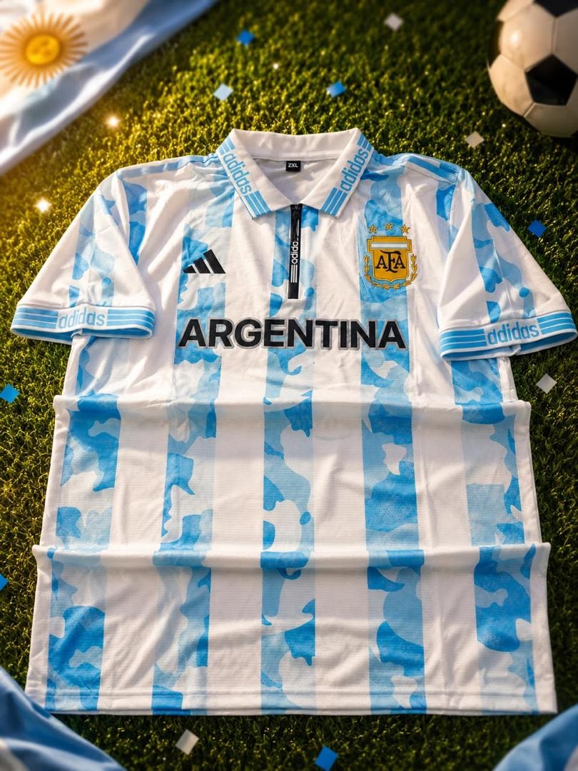 White and blue camo Adidas Argentina football jersey with crest and ARGENTINA text on grass.
