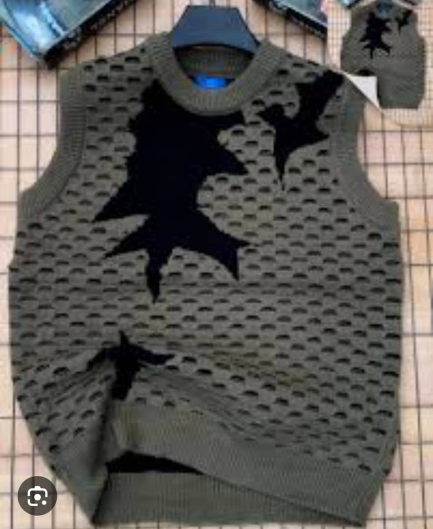 Olive armless cardi with black star patterns on hanger with inset view.