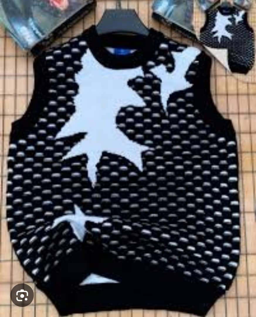 Black armless cardi with white star patterns on hanger with inset view.