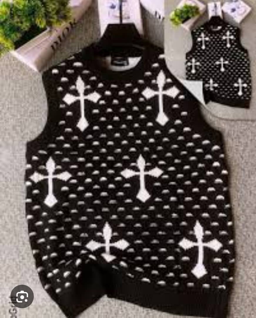 Black armless cardi with white cross patterns on hanger with inset view.