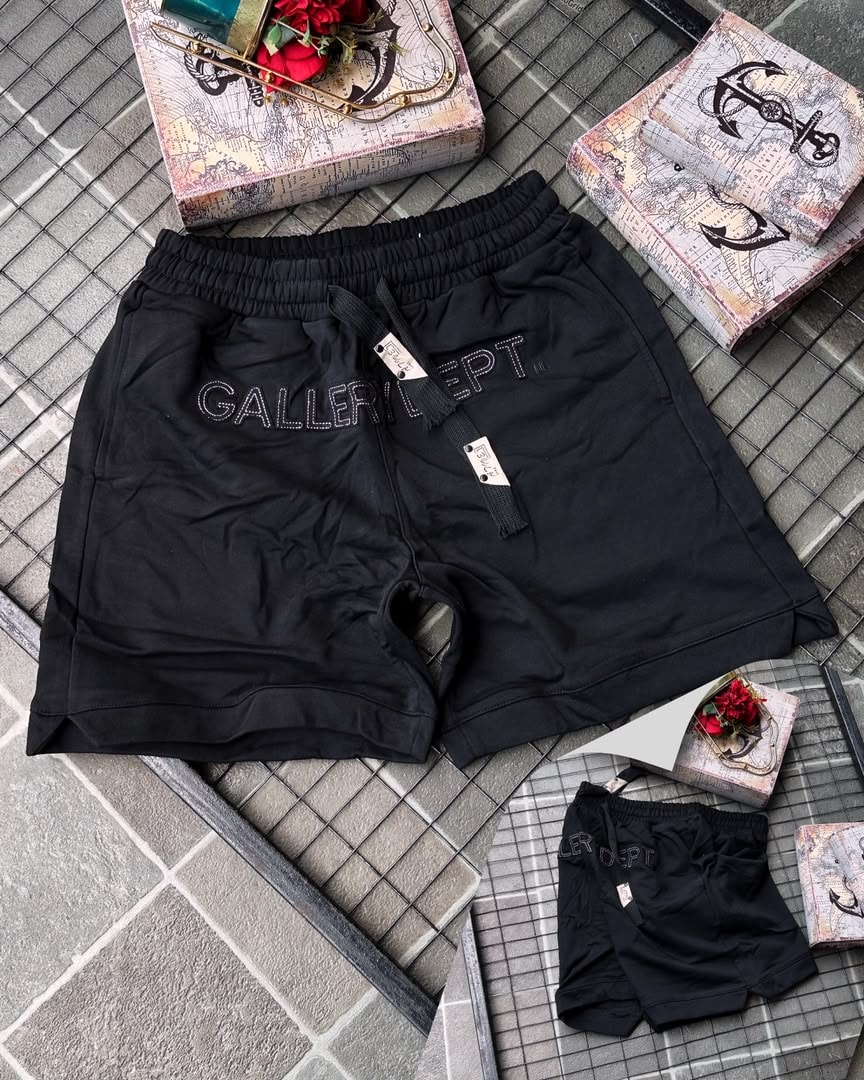 Black Gallery Dept. embroidered fleece shorts on tiled background with props.