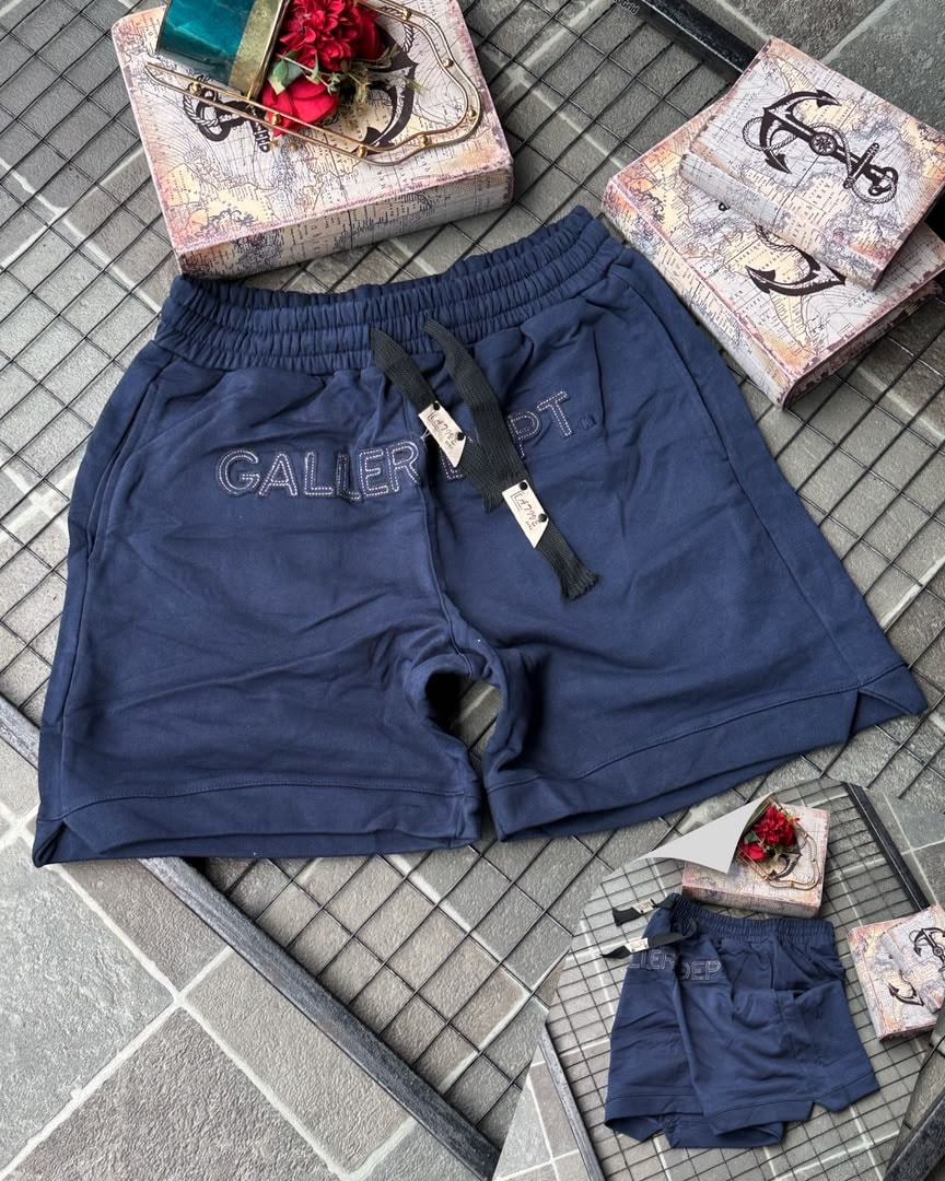 Navy Gallery Dept. embroidered fleece shorts on tiled background with props.
