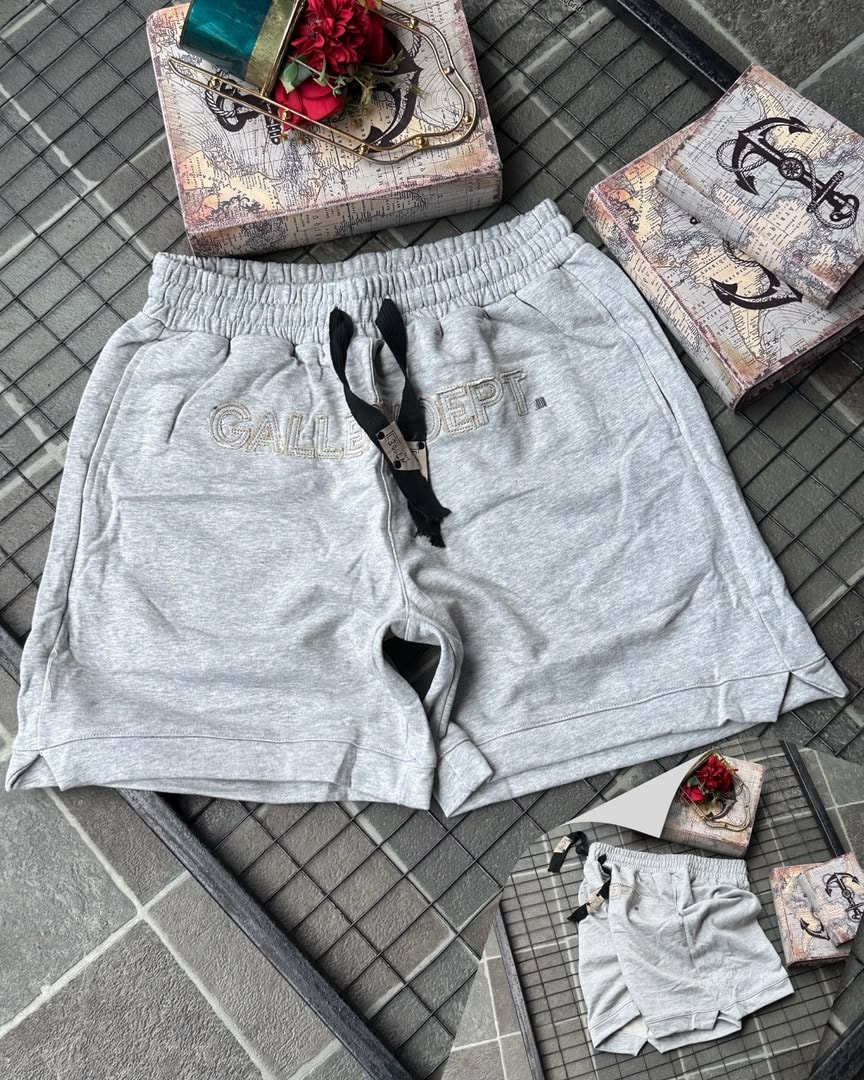 Gray Gallery Dept. embroidered fleece shorts on tiled background with props.