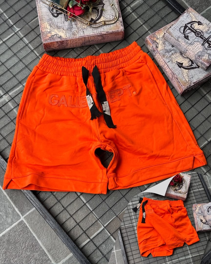 Orange Gallery Dept. embroidered fleece shorts on tiled background with props.