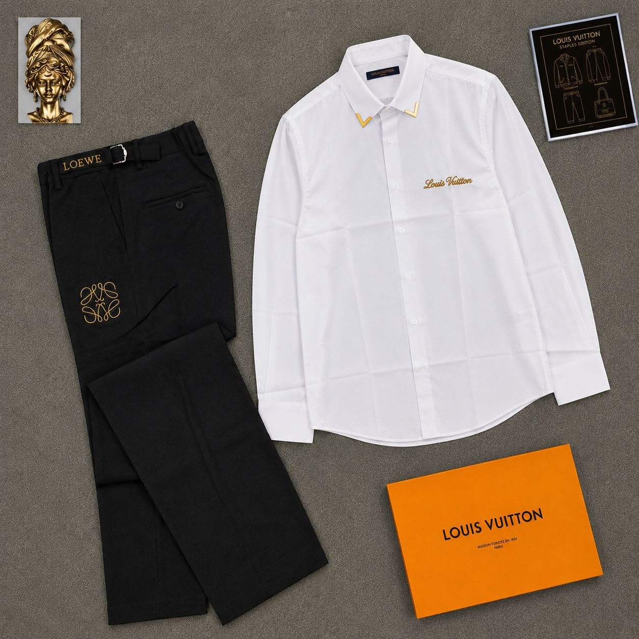 White Louis Vuitton embroidered button-down shirt with black embroidered trousers in flat lay.