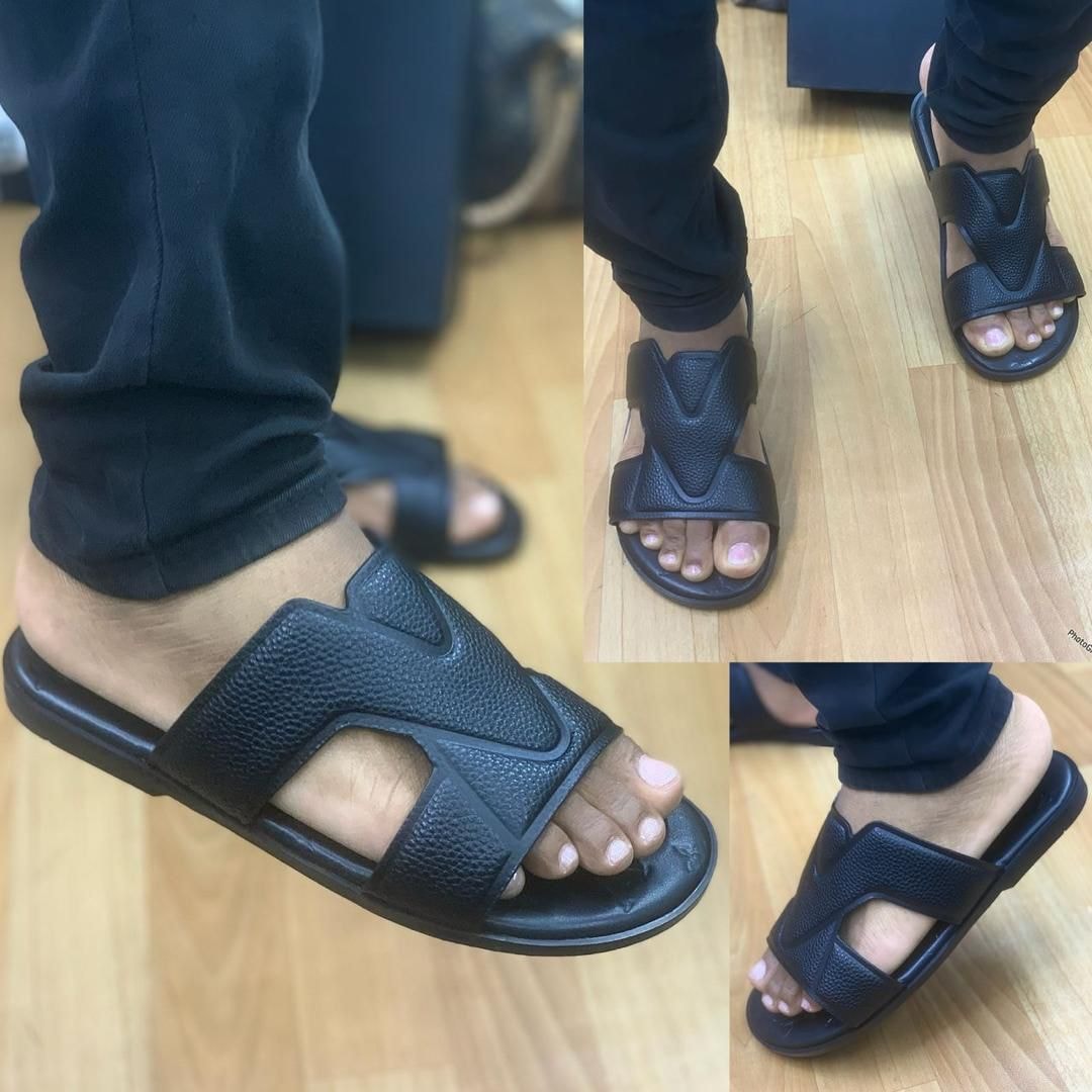 Black textured slides with V-shaped cutouts worn on feet from various angles on wooden floor.
