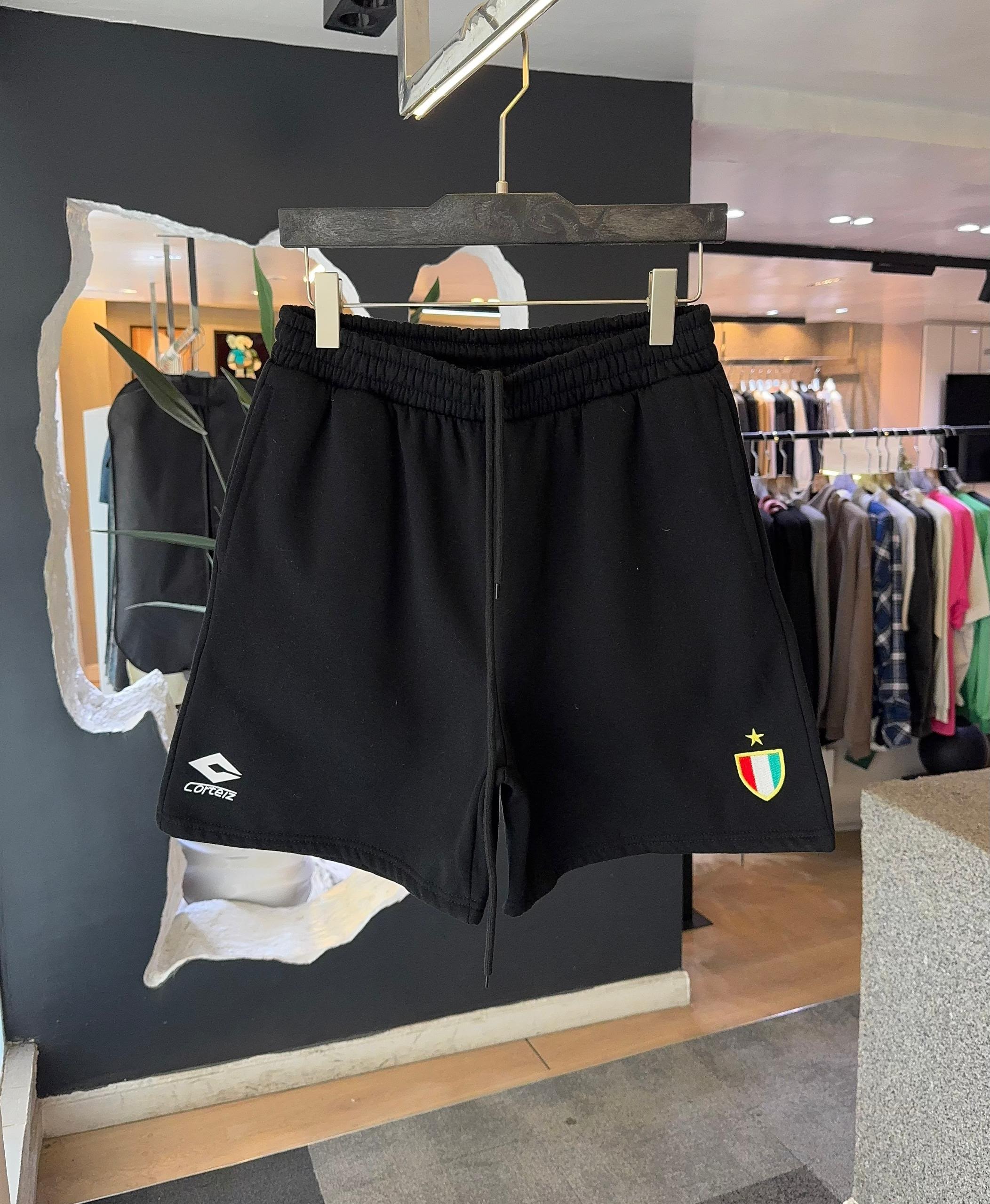 Black Corteiz fleece shorts with logo and crest hanging in store.