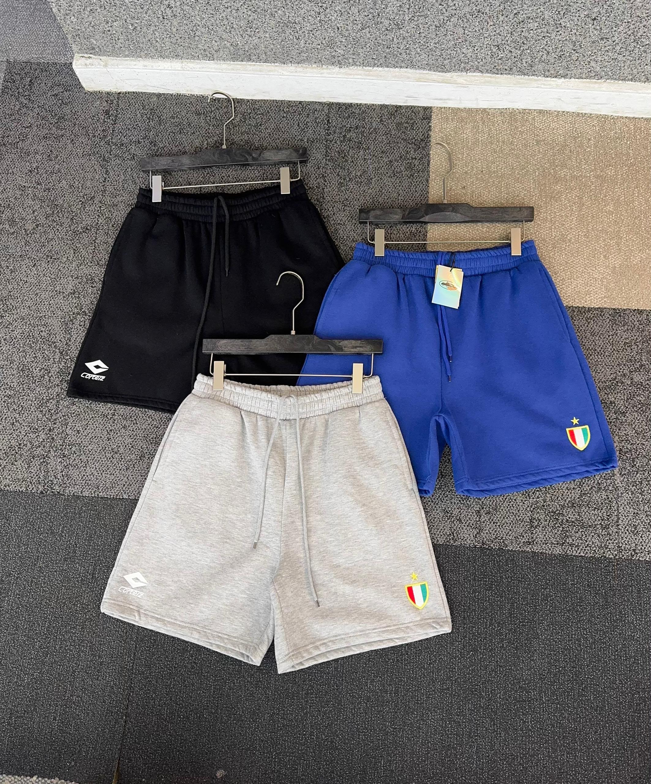Corteiz shorts in black, blue, and gray colors displayed together.