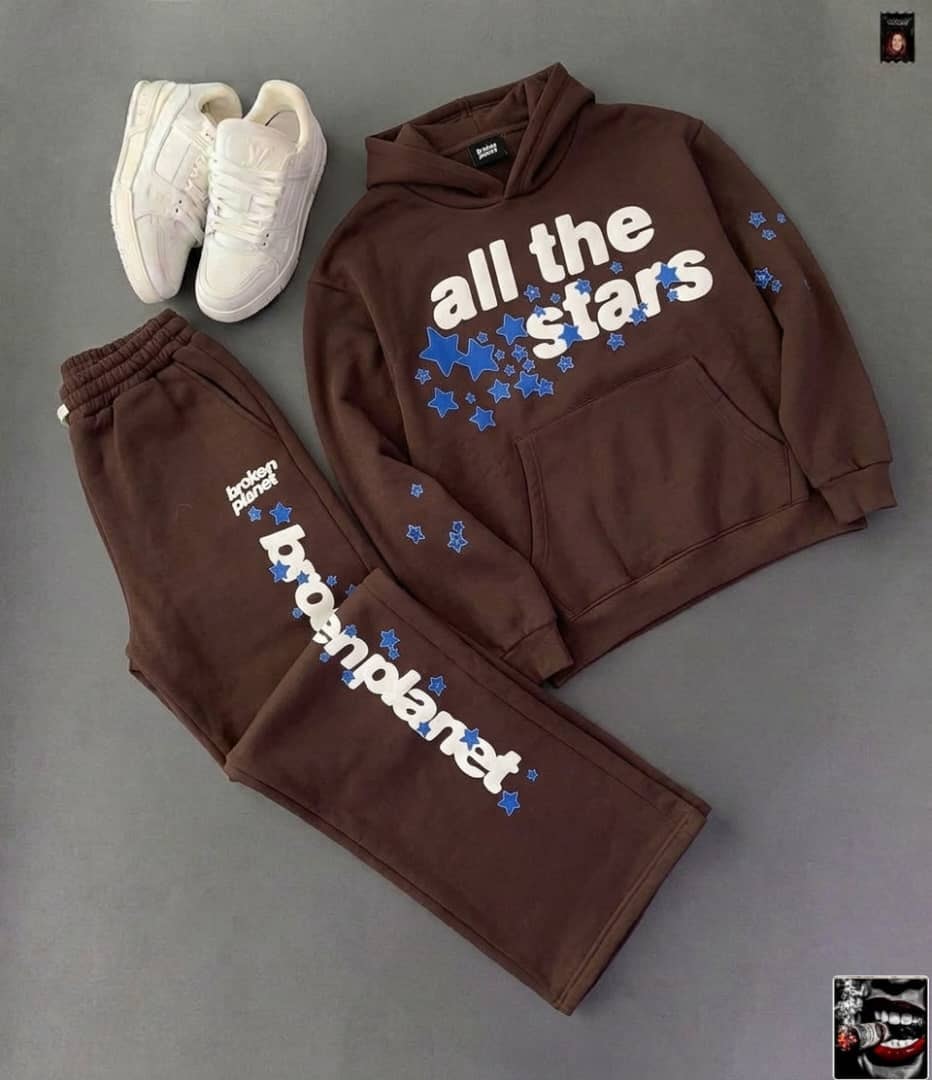 Brown hoodie and pants set with All The Stars and Broken Planet graphics and blue stars, paired with white sneakers.