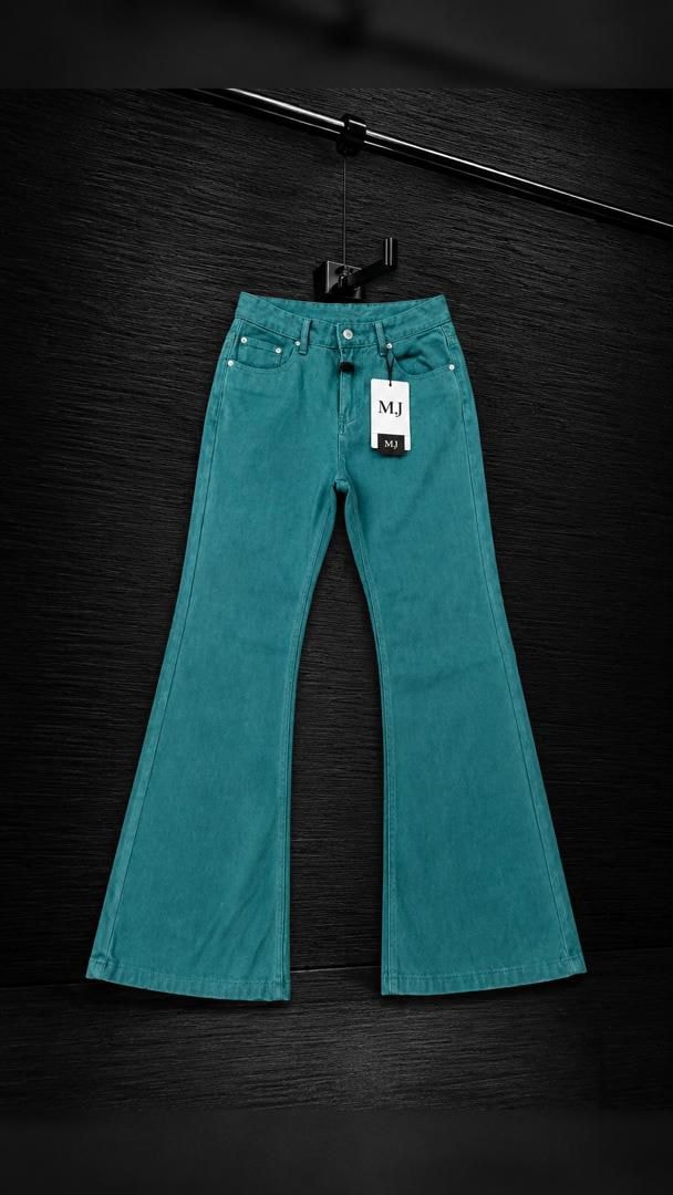 Teal plain flared jeans trousers on a hanger against dark wood, showing front view with MJ tag.