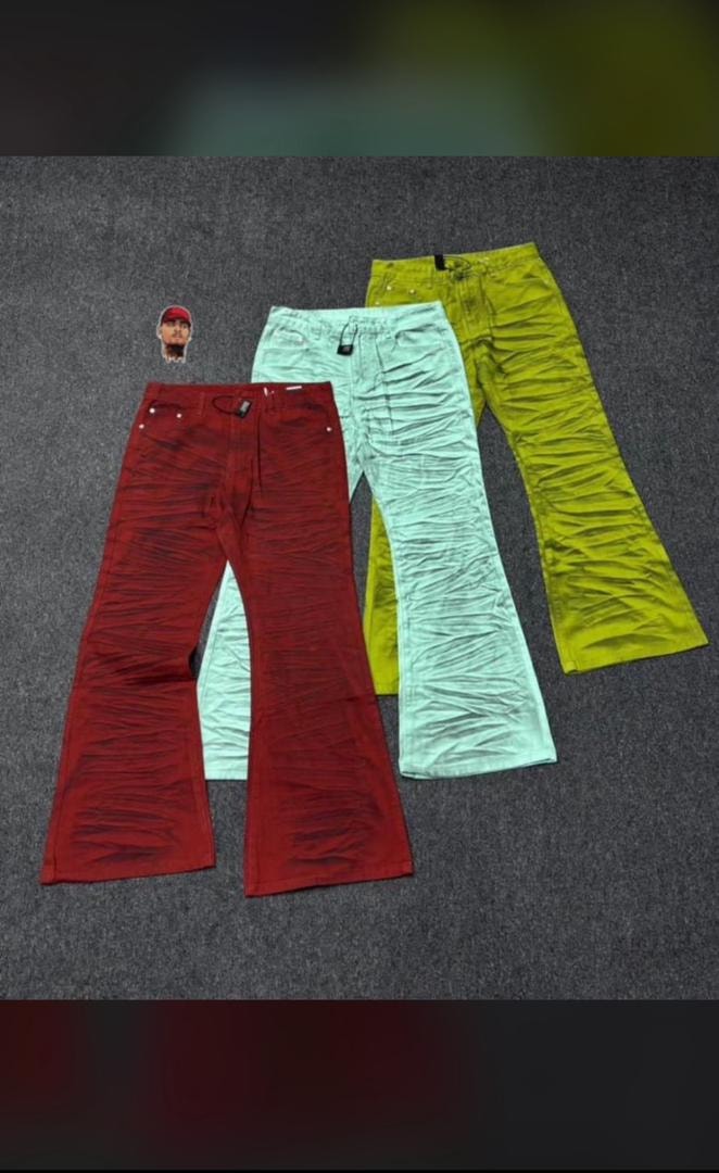 Red, green, and lime ruched flare jeans laid flat together on gray surface.