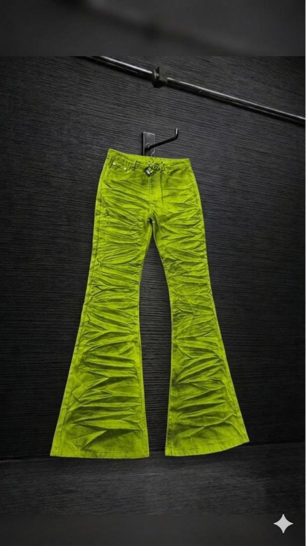 Lime ruched flare jeans hanging on hook against dark background.