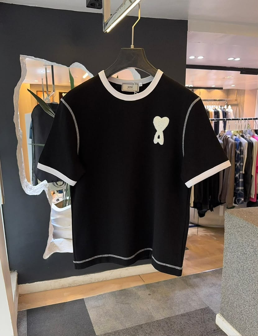 Black AMI polo shirt with white contrast trim and white heart logo on the chest.