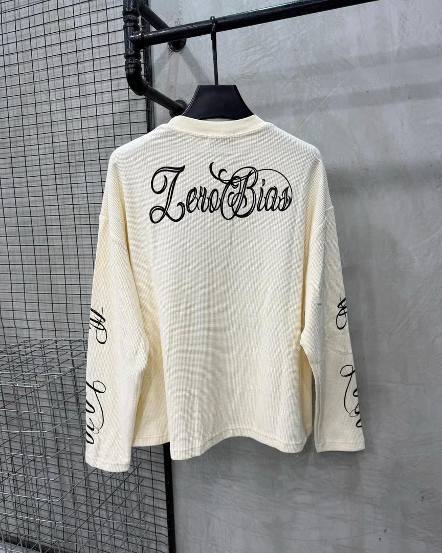 Back view of cream waffle long sleeve top showing ZeroBias cursive print and sleeve details.