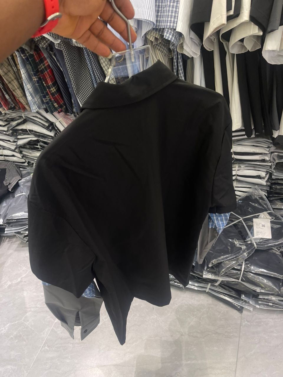 Back view of black short sleeve shirt displaying its plain back, relaxed fit and contrasting cuff details.
