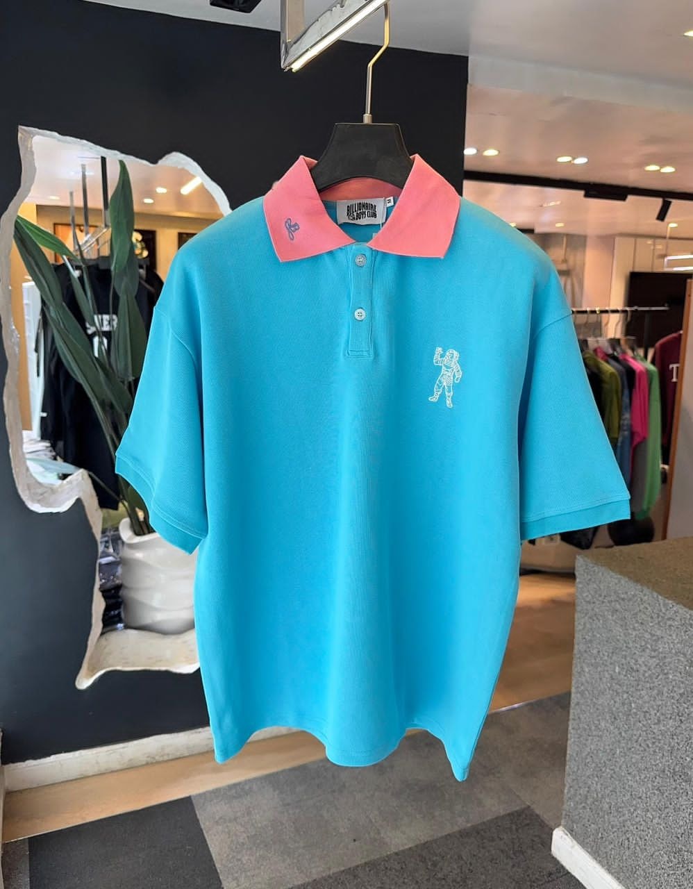 Light blue Billionaire Boys Club polo with pink collar and white astronaut embroidery on chest.