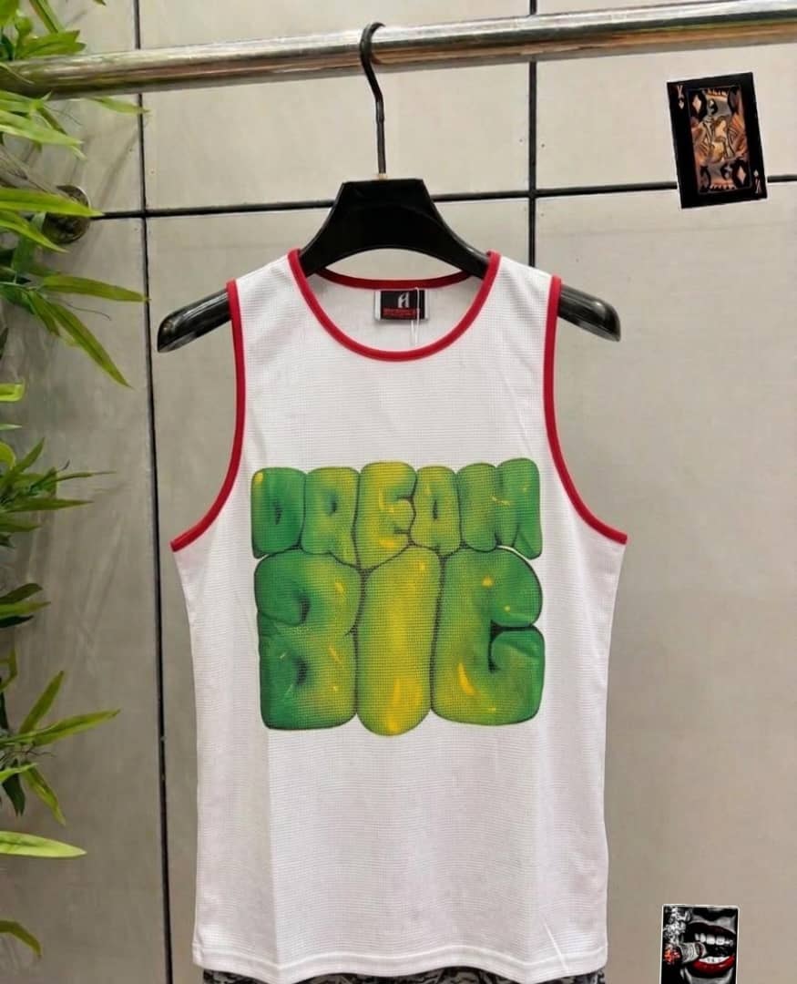 White armless tank top with red trim and large green Dream Big graphic on the front.