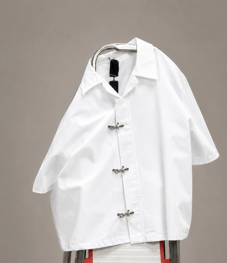 White short-sleeve shirt with silver frog closures displayed on a hanger.