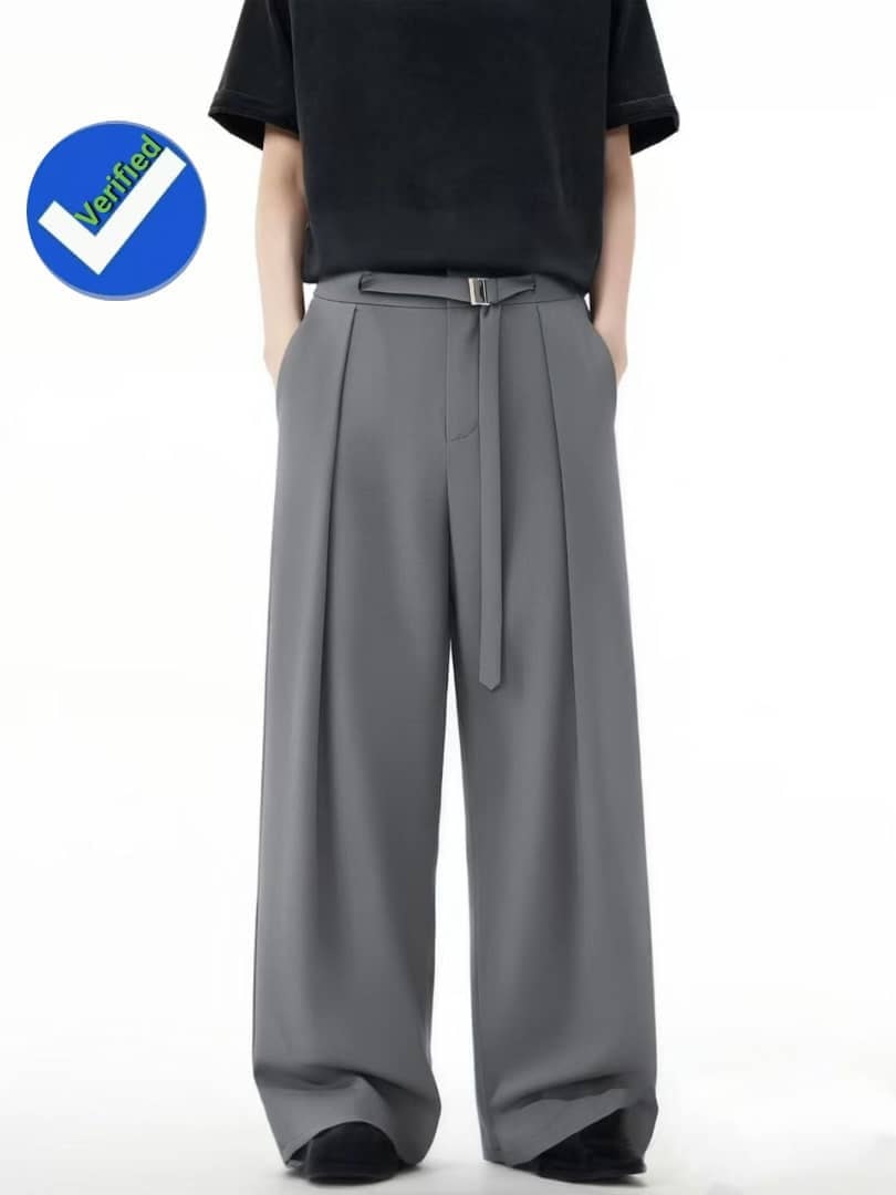 Model in gray flare trousers with belt and relaxed stance.