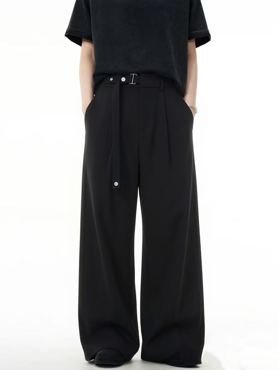 Model in black flare trousers showing self-tie belt detail and front pleats.