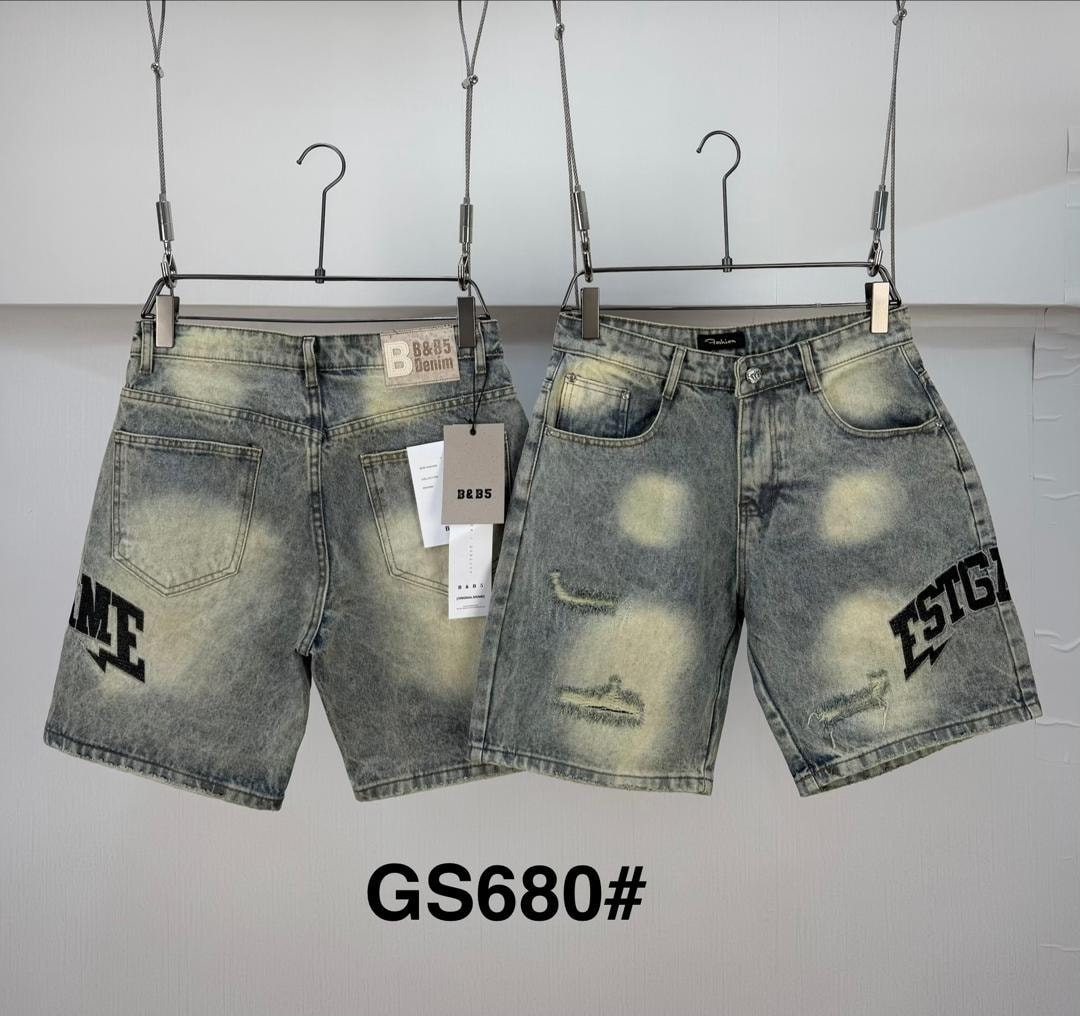 Two pairs of light wash denim jorts with prints, distressing and graphics hanging on display.