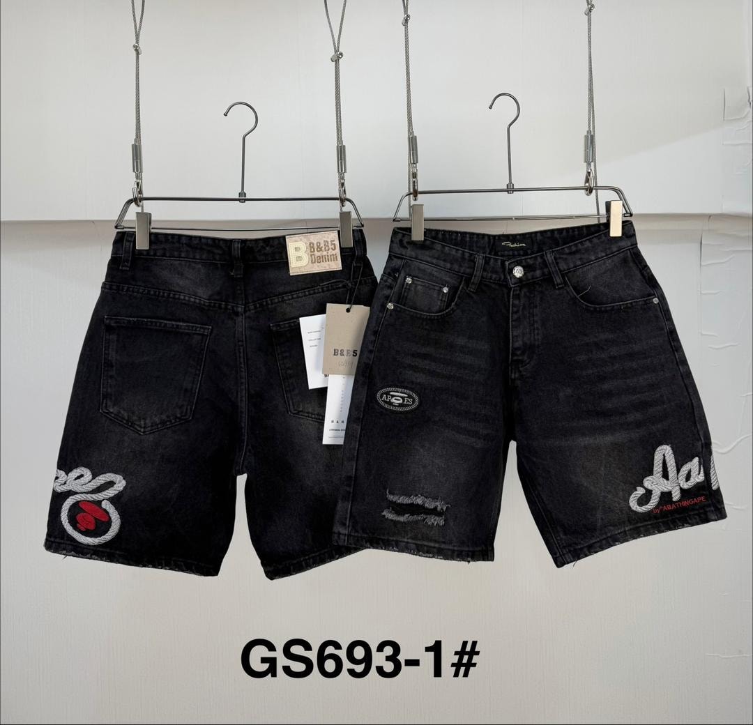 Two pairs of black denim jorts on hangers with embroidery, patches and distressing.