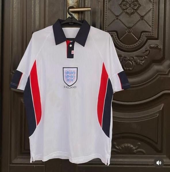 White retro England football polo jersey hanging on door.