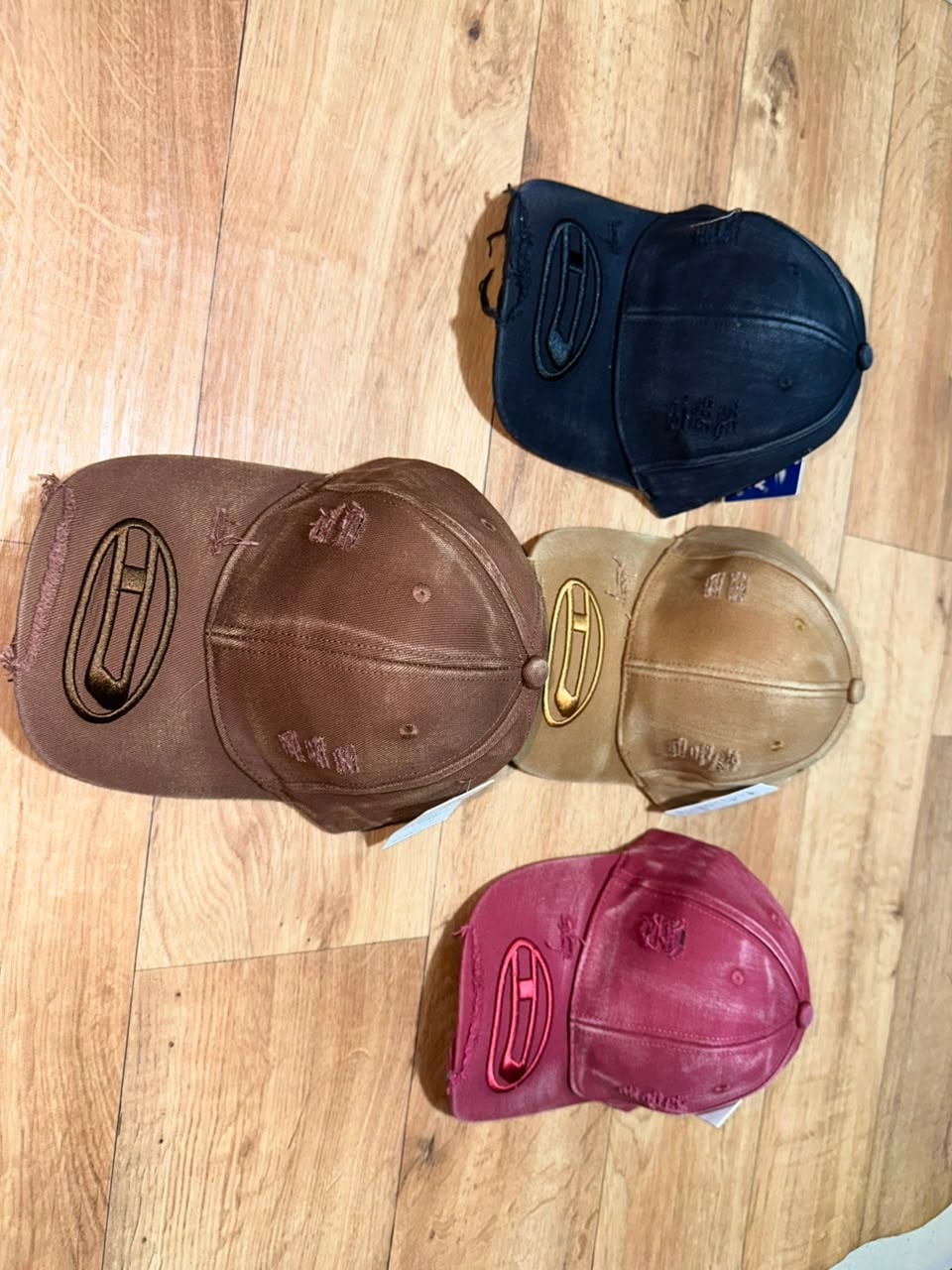 Distressed caps with H oval logo in brown, black, beige, and maroon.