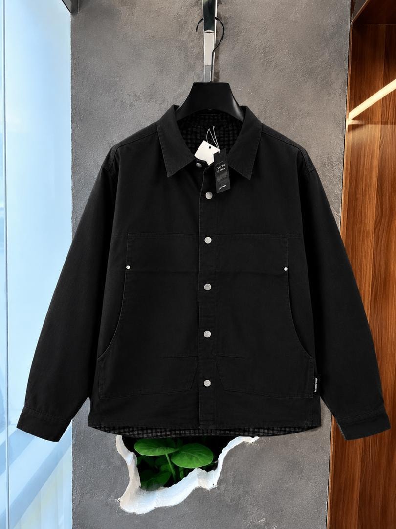 Black twill overshirt jacket hanging with visible tags and checkered lining.