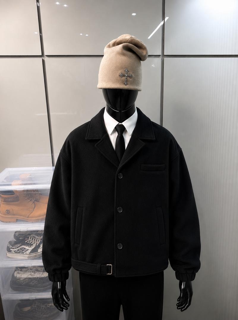 Mannequin wearing black wool jacket with white shirt, black tie and beige beanie.
