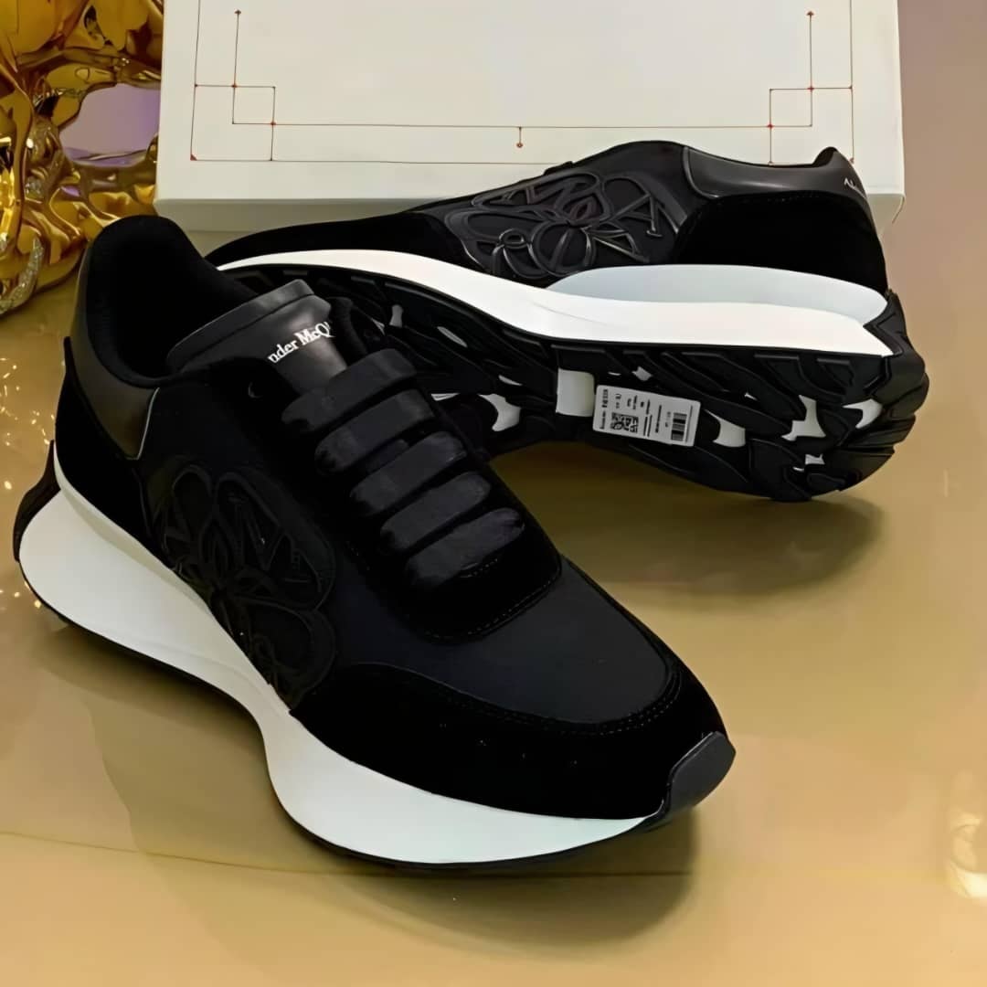 Black Alexander McQueen runner sneakers with white sole and embossed logos.