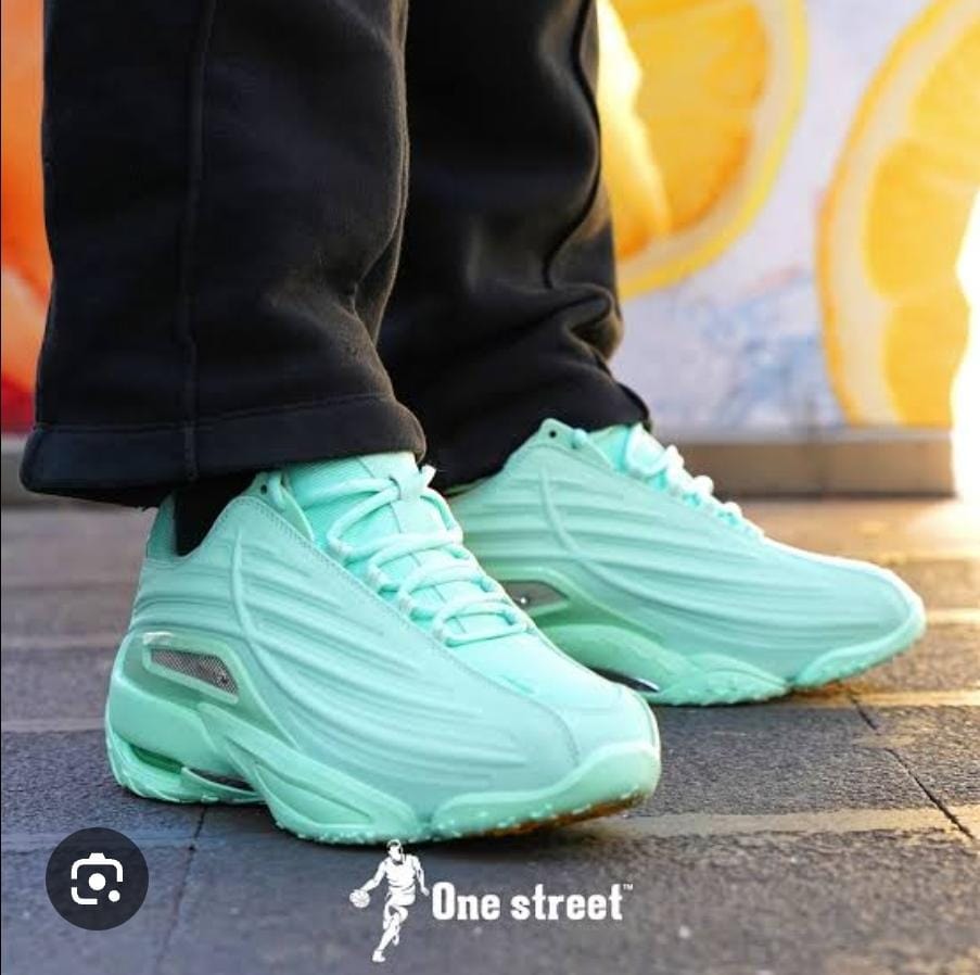 Mint green Nike Air Max Plus sneakers worn on pavement.
