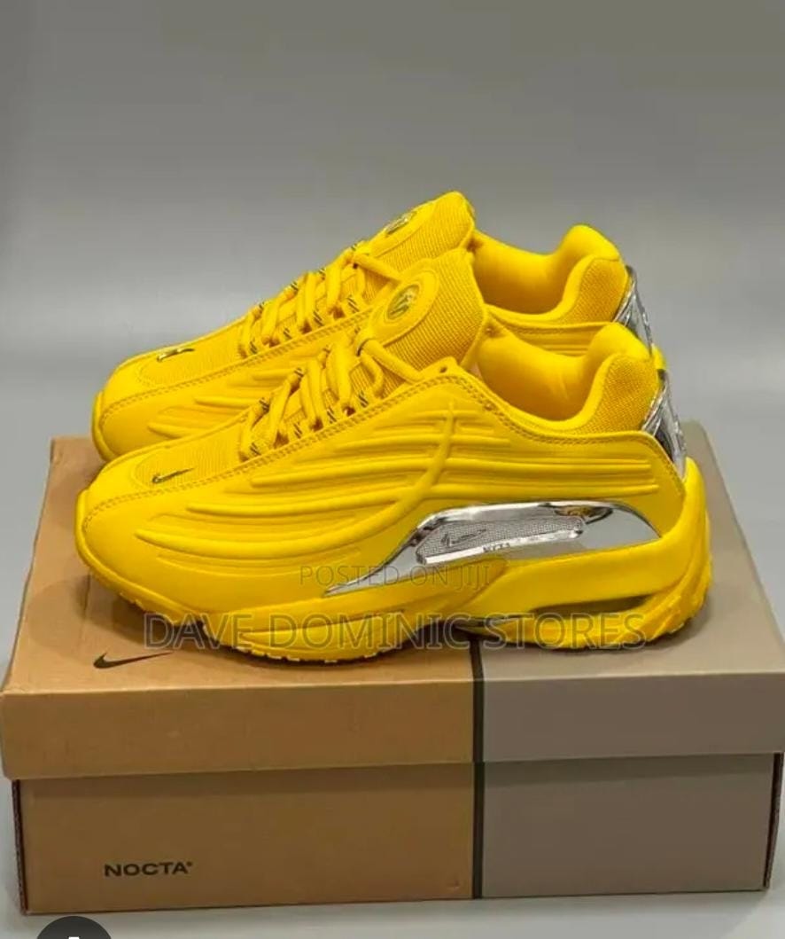 Bright yellow Nike NOCTA Air Max Plus sneakers on a shoebox.
