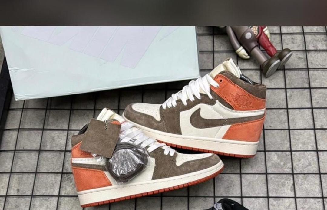 Brown orange and white Jordan 1 High sneakers with tags on tiled floor.